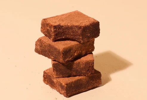 Four vegan chocolate bars stacked on top of one another, showcasing the variety of plant-based treats.